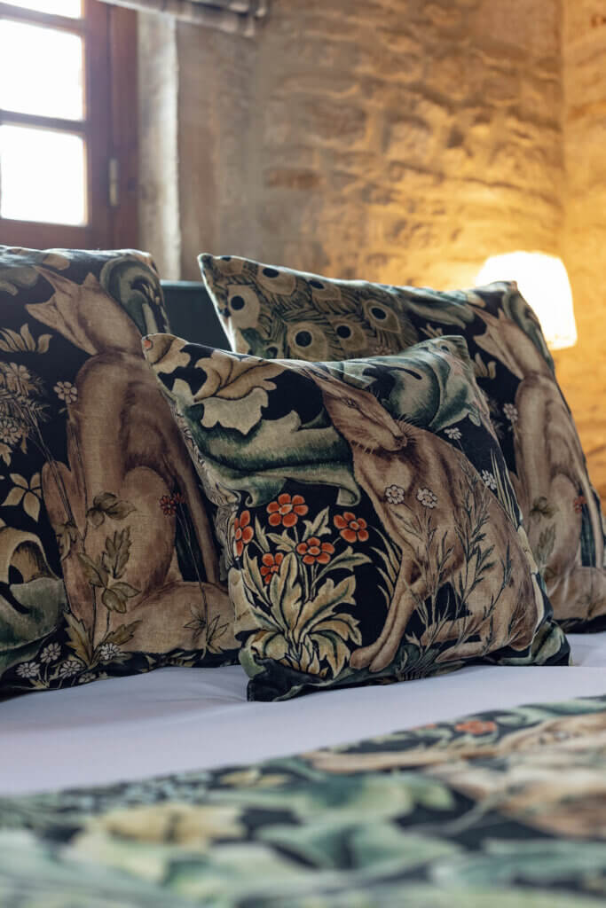 Coussins à motifs naturels sur le lit de la chambre Donjon à La Rançonnière