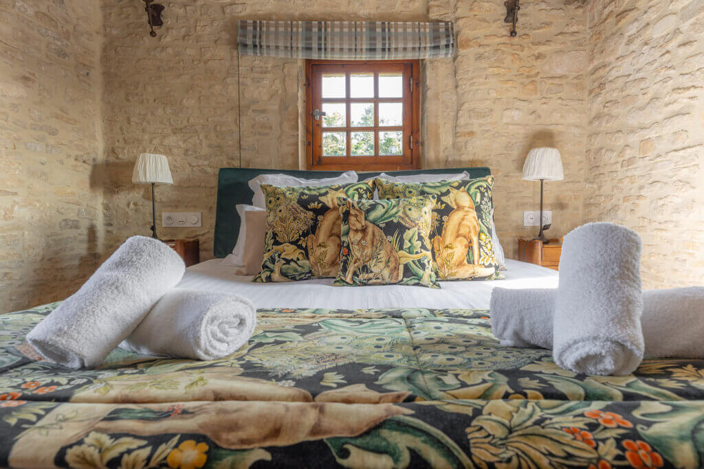 Lit double avec coussins décoratifs dans la chambre Donjon de La Rançonnière